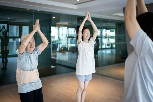 Asian woman doing exercise activity for the old elderly and child girl,family work out at leisure during COVID-19 Coronavirus pandemic,healthy senior,fitness for health care,daily workout in the gym