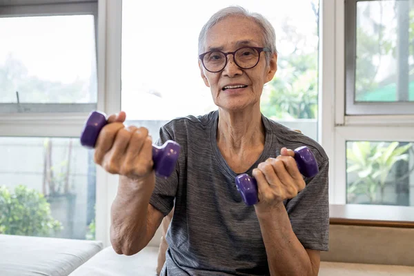 健康的で高齢者の強い 幸せな笑顔アジアのシニア女性がダンベルウェイトを持ち上げ フィットネス高齢者の祖母は ダンベル ヘルスケア 健康的なライフスタイルの概念で運動し 眼鏡を着用 — ストック写真