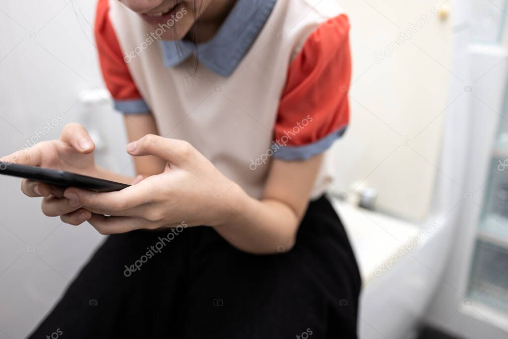 Asian student using mobile phone playing games,social network or chat with friends,sending messages,sit on toilet bowl at school,life of lazy girl study,skip school,skipping class during time to learn