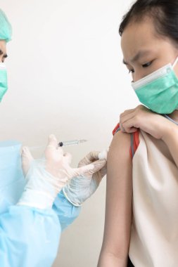 Coronavirus hastalığına karşı bağışıklık kazanmak, öğrencilere aşı olmak, aşı olmak, ilaç konseptini geliştirmek ve tedavi etmek için çocuk vücuduna şırınga enjekte ederek grip ya da COVID-19 aşısı yapan doktor