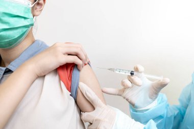 Şırınga aşısı yapan kadın doktor COVID-19, bayan kızın omzunda ya da kolunda grip, aşı yapan Asyalı hemşire, Coronavirus enfeksiyonuna karşı aşı, sağlık hizmetleri