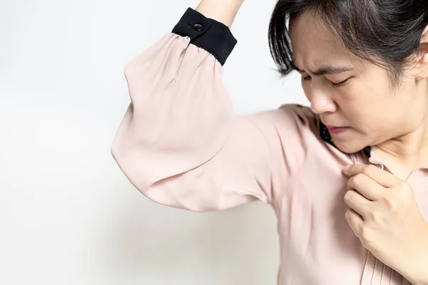 Armpit smelly or the body odor foul,Upset asian lady woman sniffing her wet armpit,smelling something stinks,body stench and sweat from hot weather,bad smell,concept of using deodorant, hyperhidrosis