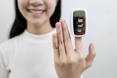 Parmak ucunda nabız oksimetresi olan Asyalı bir kızın eli, kalp atışlarını ölçen insanlar, nabız oranı, kandaki oksijen doygunluğunu ölçen insanlar, Coronavirus teşhisi ya da evdeki COVID-19