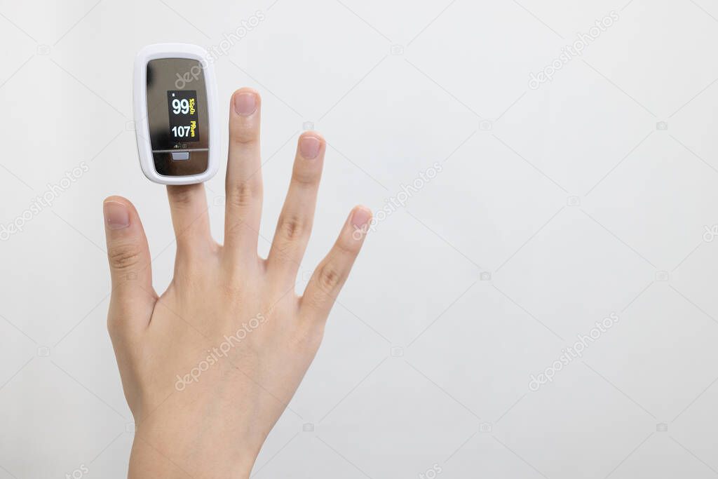 Hand of child girl with fingertip pulse oximeter on finger for examination of the lung disease,checking for Coronavirus COVID-19 infection from oxygen saturation at home,measuring heart rate (pulse)