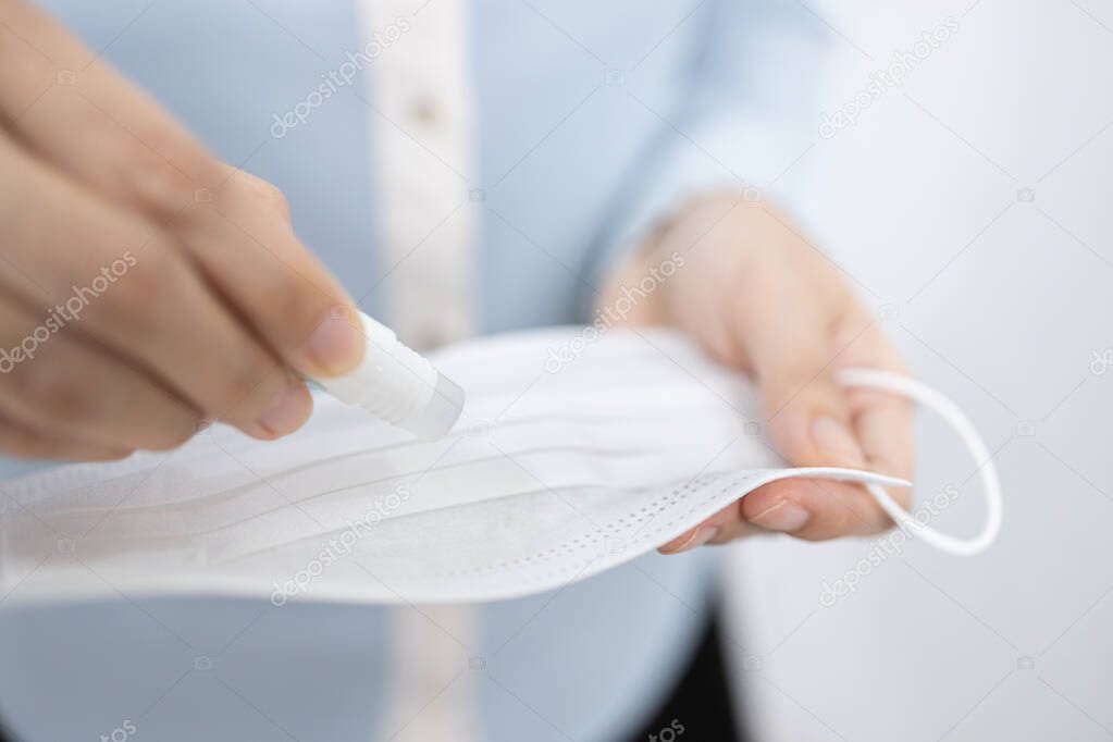 Female holding a bottle of perfume natural scent aroma,dripping the perfume into medical mask to breathe fresh while wearing it,refresh or reduce the bad breath,bad smell problem stuck in a face mask