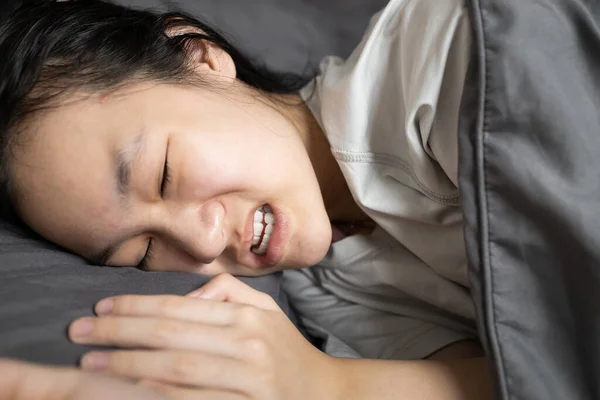 亚洲女性晚上躺在床上时遭受暴力侵害 女性在睡梦中磨牙 睡眠障碍 口腔健康问题 牙科护理 睡眠暴力观念 — 图库照片
