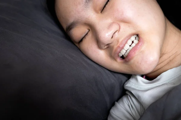 亚洲女童在晚上躺在床上时遭受暴力侵害 女性在睡梦中磨牙 睡眠障碍 口腔健康问题 牙科护理 暴食观念 — 图库照片