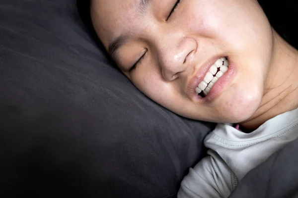 Gece yatakta yatarken bruksizmden muzdarip Asyalı kız çocuğu, uyurken dişlerini gıcırdatan kadın diş gıcırdatma, uyku bozuklukları, oral sağlık sorunları, diş bakımı sağlık sorunları, bruxism konsepti