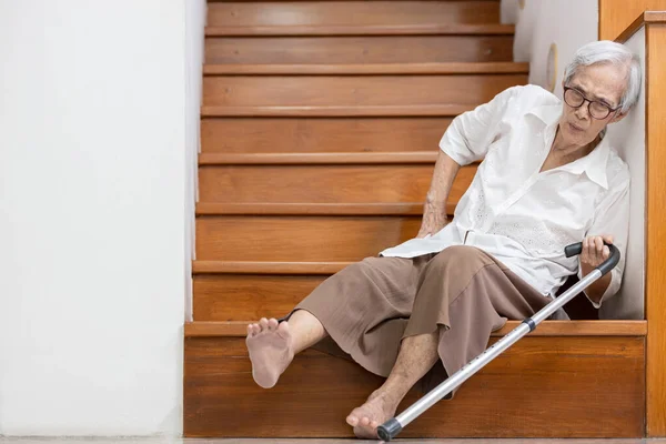 階段の床に腰や背中に痛みを感じながら座っていたおばあさんは 階下を歩くとバランスが崩れ 高齢者は転倒し めまいによって負傷しました — ストック写真