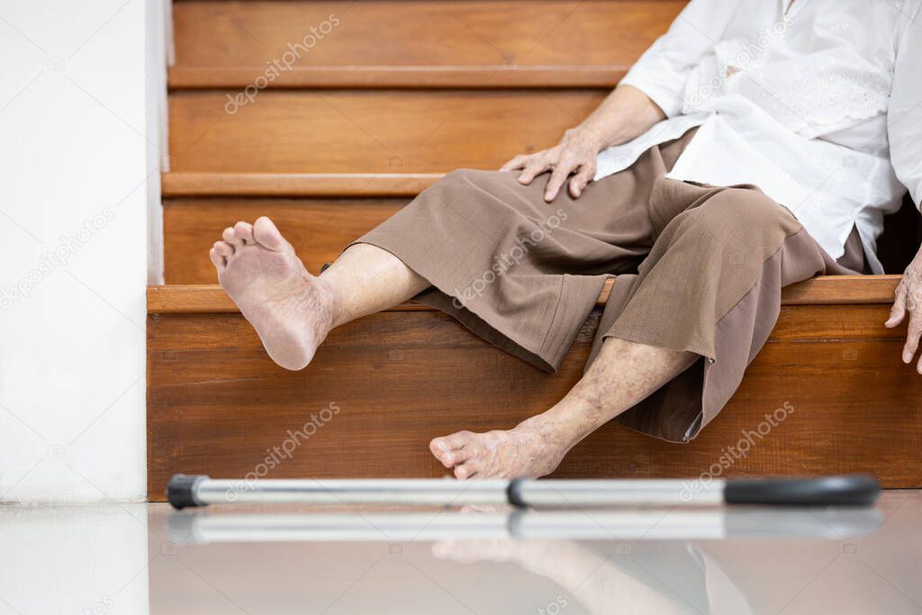 Old elderly lies unconscious on the floor of the staircase after slipping,tripping or losing balance while walking,moving with difficulty,senior woman fell down the stairs,an accident in the house