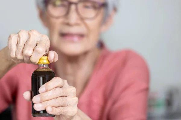 亚洲老年妇女竭力想摘下瓶盖 打开瓶盖 给老年人或妇女打开瓶盖有困难 喝酒有困难 生活有问题 — 图库照片