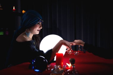 Falcı, geleceği ya da kaderi tahmin etmek için müşterinin avuç içini okuyor..