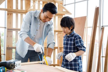 Baba oğluna marangozluk atölyesinde testere kullanmayı öğretiyor. Aile kavramı evde birlikte hobi yapıyor..
