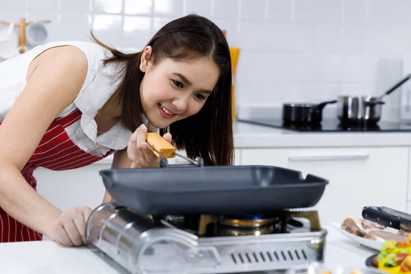 Asian woman chef using camping stove to cook food in kitchen. Concept woman preparing meals at home.