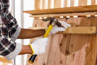 Marangoz, marangozluk atölyesinde kereste üzerinde çekiç kullanır..