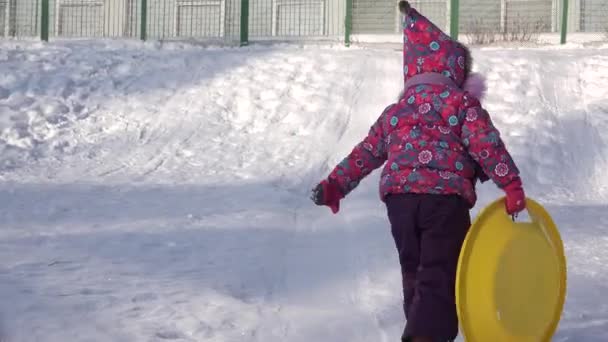 Παιδί βόλτα σε ένα πιάτο πάνω σε λόφο, παιδί έλκηθρο με το χειμώνα. 4 k Ultrahd, Uhd — Αρχείο Βίντεο