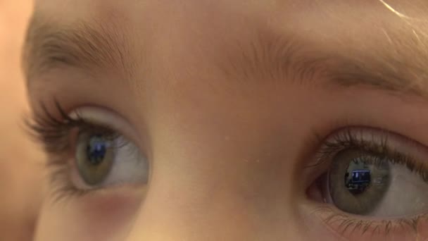 Closeup of Happy Baby Girl Eyes Looking TV, Reflections in Eyes. 4K UltraHD, UHD — Stock Video