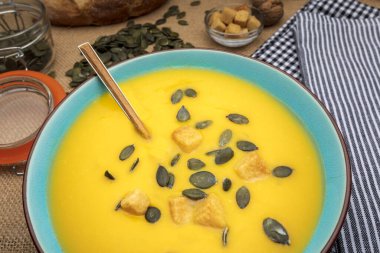 Balkabağı kremasını kaseye koy. Kıtır ekmekler ve kabak tohumlarıyla.