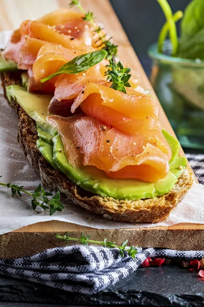 Avokado ve sebzeli (ıspanak lahanası, domates, kekik) iştah açıcı ve sağlıklı füme somon tostu. Ev yapımı görünüş.