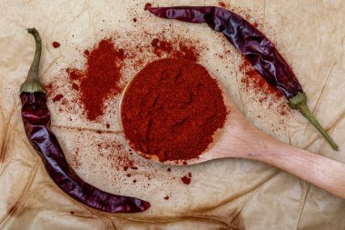 Tahta kaşıkta kırmızı biber ve kurutulmuş biber içeren kağıt dokusu (baharat koleksiyonu). Kırsal arka planda. Üst görünüm.