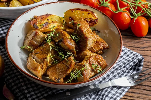 Tavada pişmiş, küp küp kesilmiş domuz filetosunun iştah açıcı güveci. Kızarmış ve altın patatesli, sarımsak, tuz, kekik ve taze domatesli. Ev yapımı görünüş. Yakın plan.