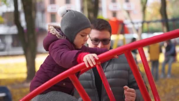 Far med barn leker på lekplatsen, höst, gula löv. Aktivitet för barn utomhus — Stockvideo