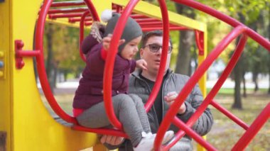 Çocuklu baba çocuk parkında oynuyor, sonbahar, sarı yapraklar. Açık hava çocuk aktivitesi