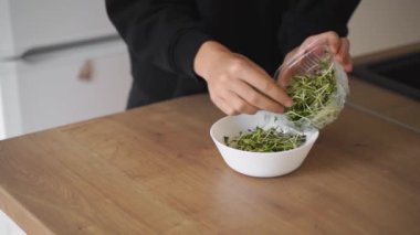 Genç bayan turp mikroyeşilliklerinden salata hazırlıyor. Sağlıklı yaşam tarzı, süper yiyecekler