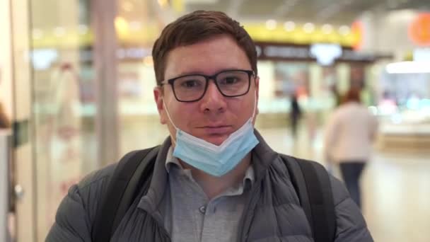 Biały młodzieniec w czarnej masce wielokrotnego użytku. pandemia zakrzepowo-19. niewłaściwe zużycie maski na twarz — Wideo stockowe