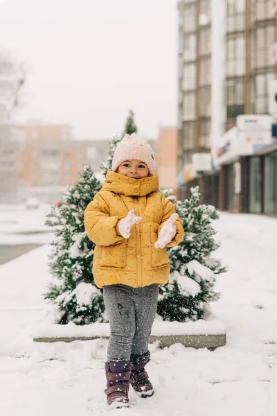 Criança em roupas amarelas no dia nevado fora com pinheiros cobertos de neve — Fotografia de Stock