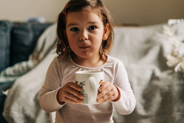 Niña caucásica bebiendo cacao de la taza en casa. Navidad Bokeh luces — Foto de Stock