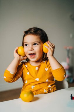 Beyaz kız mandalinalarla eğleniyor. Sağlıklı çocuk diyeti. C vitamini ile bağışıklık güçlendirici