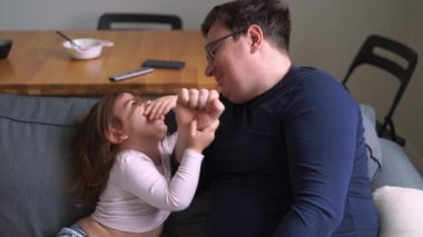 Kanepede çocuklu bir baba. Çocuklu rahat bir ev aktivitesi. Babalık