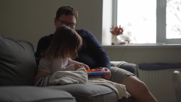 Far med barn på soffan. Mysig hemaktivitet med barn. faderskap — Stockvideo
