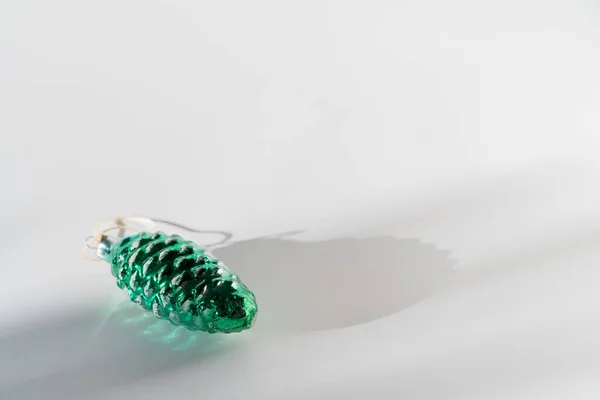 Green pine cone glass vintage christmas bauble on white background with sunlight and shadow — Stock Photo, Image