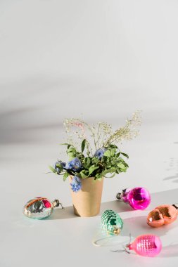 Kağıt bardakta çiçekler, geçmişe dönük noeller, beyaz arka planda mücevherler, son moda güneş ışığı ve gölgeler.