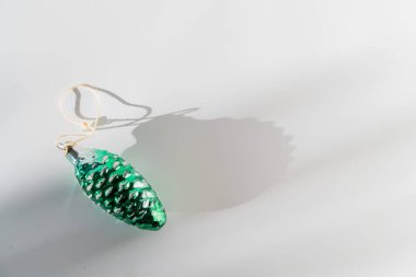 Yeşil kozalaklı cam vintage Noel şarabı beyaz arka planda güneş ışığı ve gölgeyle takılıyor.