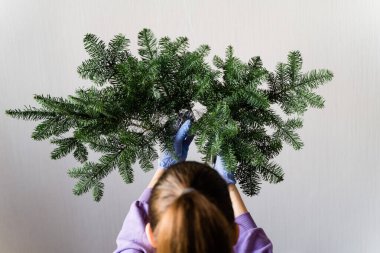 Asılı çam çelenkli bir kız kafası. Kadın çiçekçi çalışıyor. Noel Arası Dekorasyonu