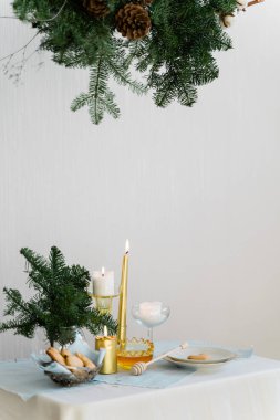 Noel için estetik tasarım. Çam nobilisleri, çelenkler, mumlar ve masa süslemeleri asılı. 