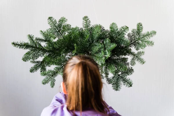 Cabeza de chica con una guirnalda de pino colgante. Una florista trabajando. Decoración de Navidad DIY —  Fotos de Stock