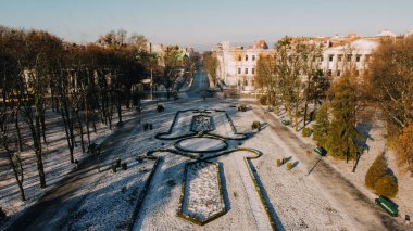 European town Poltava in Ukraine. Snowy central park of the city, land design, old cadet corp clipart