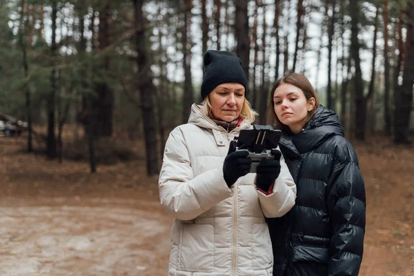 Mujer caucásica con hija adulta volando avión no tripulado en el bosque de otoño. — Foto de Stock