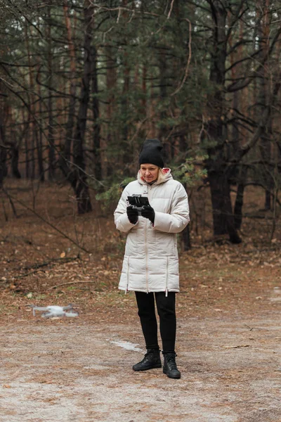 Mujer caucásica volando aviones no tripulados en el bosque de otoño. Mujer de mediana edad conocedora de la tecnología. Hobby moderno — Foto de Stock