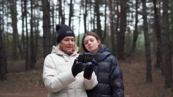 Donna caucasica con figlia adulta che vola drone aereo nella foresta autunnale. — Video Stock