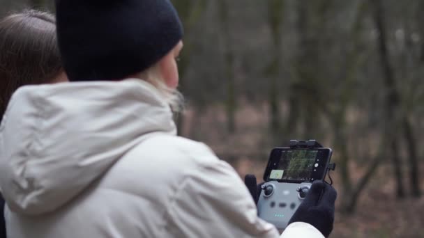 Donna caucasica con figlia adulta che vola drone aereo nella foresta autunnale. — Video Stock