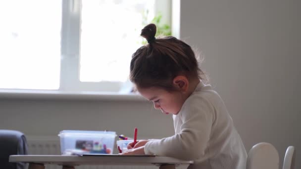 Kleinkind Mädchen mit ausgefallenen Haarbüschel Malbuch allein. Schlechte Körperhaltung. Vorschultätigkeit, Unschooling zu Hause. Kreativer Künstler — Stockvideo