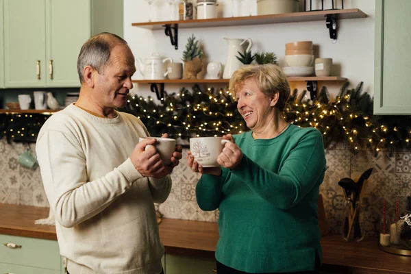 Photo of 60s elderly couple enjoying life at the kitchen with mugs of coffee. st valentines day of old couples in love. stop ageism discrimination