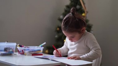 Süslü saçlı, çörek boyama kitabı olan küçük bir kız. Kötü duruş. Okul öncesi etkinlik, evde eğitim. Yaratıcı sanatçı