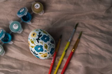 Çiçek desenli boyanmış tavuk yumurtası. Paskalya tatili için çocuklarla el işi. Botanik dekorasyonu. Keten doğal bez arka plan. Bahar tatili için el işi