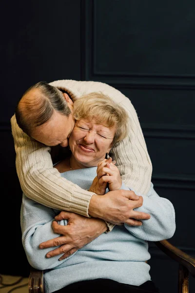 Porträt eines alten Ehepaares, das sich umarmt und lächelt. Dunkelblauer Hintergrund. Glückliche Liebende im Ruhestand. Schluss mit Altersarmut. — Stockfoto